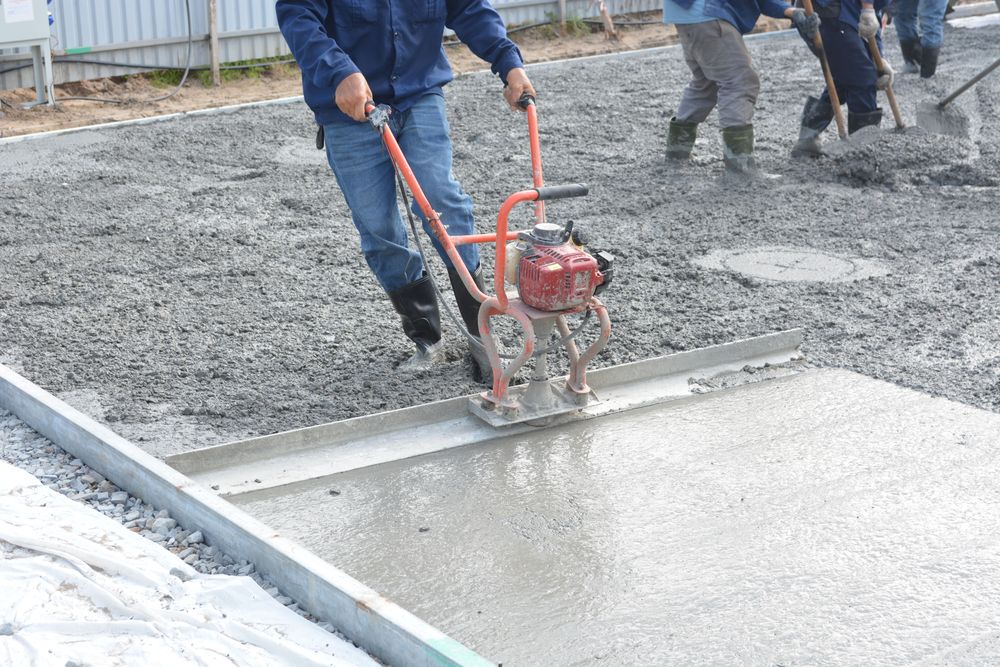 Ouvriers lissant une dalle de béton fraîchement coulée